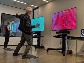 Visitor gesturing in front of an interactive artwork at the V&A Digital Design Weekend